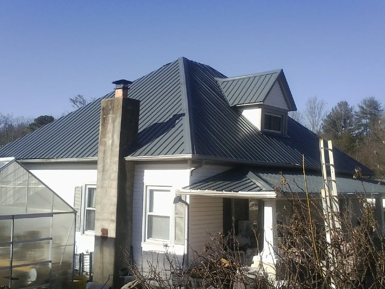 Dark blue standing seam metal roof on a white farmhouse with dormer — Slate & Tile Roof Repair by Roofing Brothers in Charlton