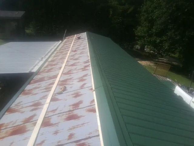 Old rusted panels beside newly installed green metal roofing — Wind Damage Roof Repair by Roofing Brothers in Charlton
