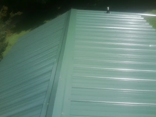 New green metal panels meeting at the ridge of a roof — Flat Roof Repair work by our crew in Charlton