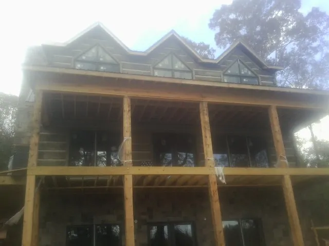 Dormers and porch framing on a large log home under construction — Roof Coating work by our crew in Charlton