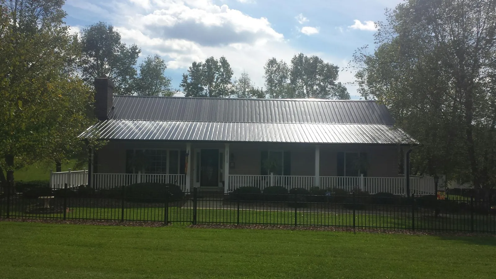 Gray metal roof on a brick ranch with a full width front porch — Gutter Guard Installation work by our crew in Charlton