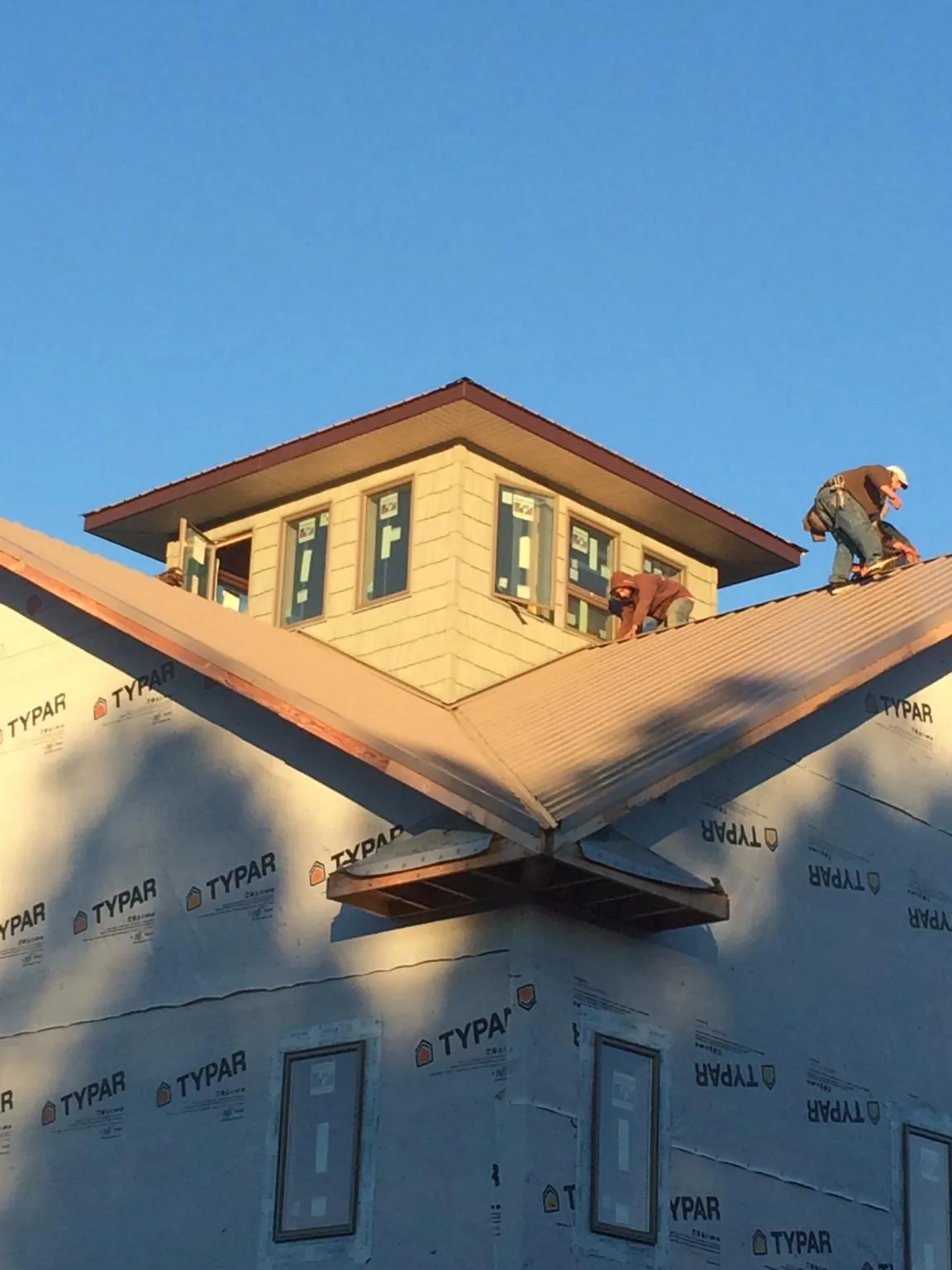 Roofers working around a rooftop cupola on a new metal roof at sunset — Roof Waterproofing in Charlton by Roofing Brothers